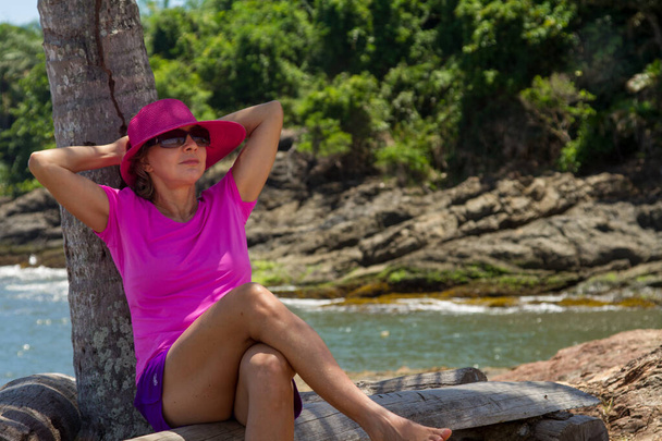 Donna che si rilassa in spiaggia indossando un abito rosa colorato - Foto, immagini