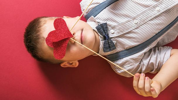 Five year old smiling boy holding a red heart on eays  symbol of love, family, hope. Backgrounds for cards on Valentine's Day or social posters about the preservation of the family and children. - Photo, Image