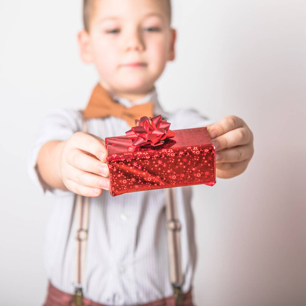 Fünfjähriger lächelnder Junge schenkt am Valentinstag ein rotes Geschenk. - Foto, Bild