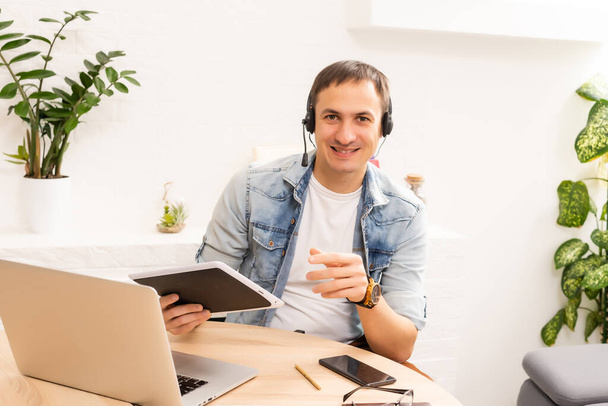 Felice giovane uomo sorridente, mentre lavora sul suo computer portatile per ottenere tutti i suoi affari fatti la mattina presto - Foto, immagini