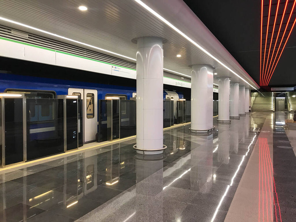 Почти пустая городская станция метро с отходящим поездом. - Фото, изображение