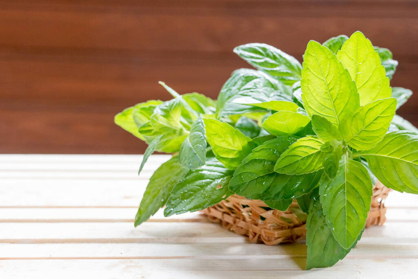 Fresh mint in bowl on wooden table. Selective focus.Peppermint in small basket on natural wooden background,Mint leaves under sun rays.Copy space - Photo, Image