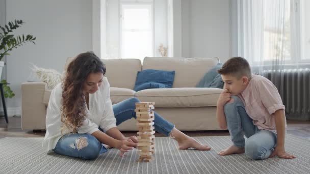 Anya és fia ülnek a padlón a lakásban. Játszanak összeszerelés piramis fából készült bárok. - Felvétel, videó