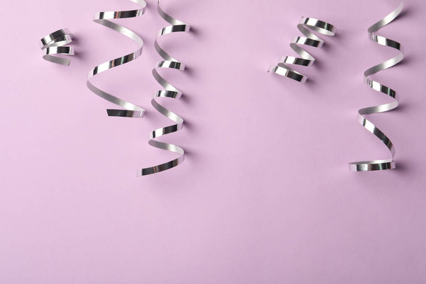 Shiny silver serpentine streamers on pink background, flat lay. Space for text - Foto, immagini