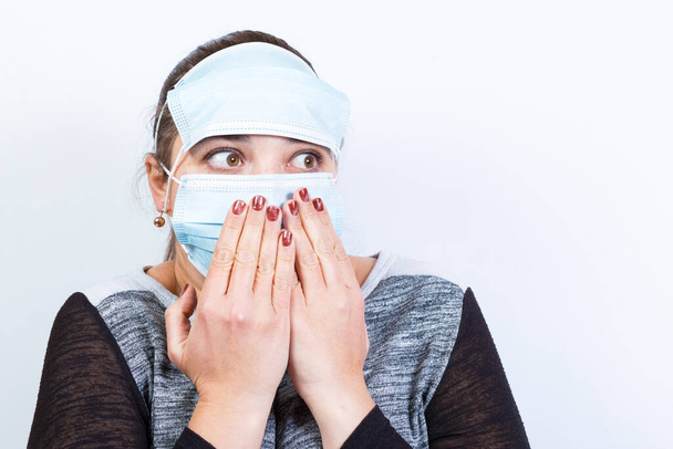 Mujer joven lleva dos máscaras médicas en la cara, con la cara asustada lloking un lado. - Foto, imagen