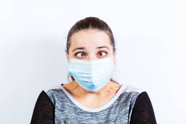 Yong mooie vrouw grimas in medisch masker op een witte achtergrond. - Foto, afbeelding