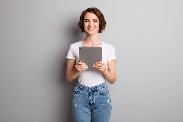 Photo of young girl wear casual outfit hold pc tablet happy smile confident isolated over grey color background - Foto, Imagen