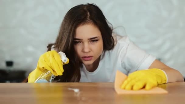A fiatal nő otthon takarít. Egy barna női modell főzőfelületet tisztít a konyhában. A lány feltakarítja a mocskot a lakásban. - Felvétel, videó