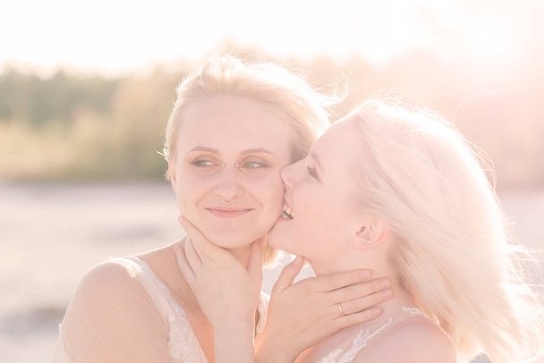 Due spose donne in abito bianco con capelli biondi che si abbracciano, matrimonio lesbico - Foto, immagini