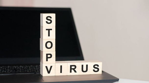 Stop Virus - tekst napisany na drewnianym bloku na klawiaturze komputera na czarnym tle. koncepcja - Zdjęcie, obraz