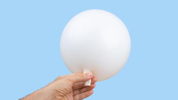 Valkoinen ilmapallo räjähtää sinistä taustaa vasten - Materiaali, video