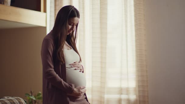 Giovane donna felice godendo la sua gravidanza, accarezzando la sua grande pancia, sentendosi unita con il suo bambino, rallentatore - Filmati, video