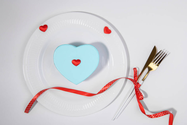 Romantic table setting with heart shape blue gift with red heart decoration on a white background. Gift for him for Valentines Day, Birthday or Fathers Day - Valokuva, kuva