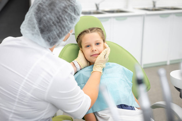 Bambino con sorriso carino siede alla sedia del dentista con tovagliolo. Controllo dell'avvio del dentista - Foto, immagini
