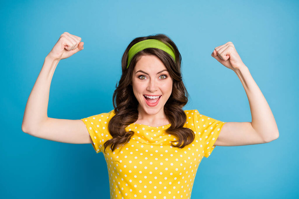 Portrait of good mood energetic girl show her biceps hands isolated over blue color background - 写真・画像
