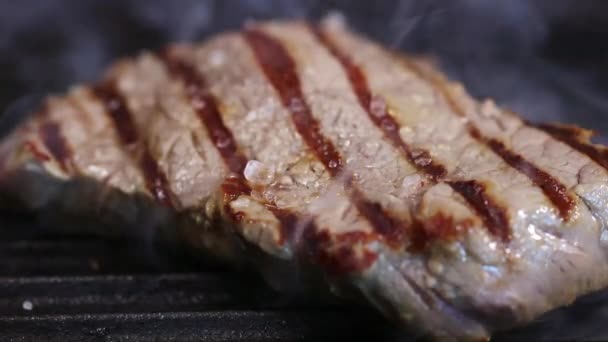 stek wołowy jest smażony na gorącej patelni grillowej - Materiał filmowy, wideo