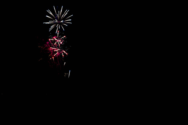 fuochi d'artificio bianchi e rosa sopra il cielo nero con spazio di copia - Foto, immagini