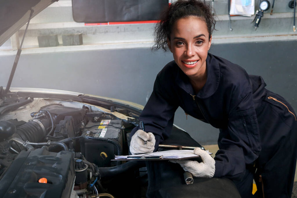 Female auto mechanic working in garage, car service technician checking and repairing the customer car at automobile service center, vehicle repair service shop concept. - Zdjęcie, obraz
