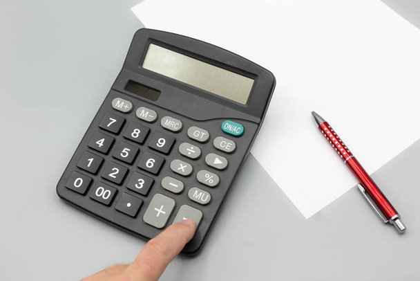 calcolatrice su scrivania con sfondo grigio, carta da penna. verticale - Foto, immagini