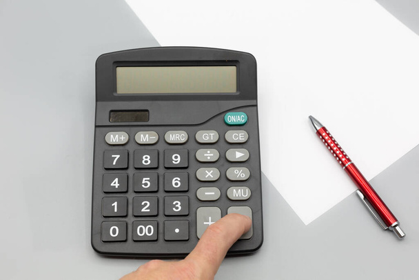 Kalkulator w biurze z papieru i pióra na szarym tle. Poziomy - Zdjęcie, obraz