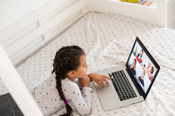 Petite fille étudiant en ligne en utilisant son ordinateur portable à la maison - Photo, image