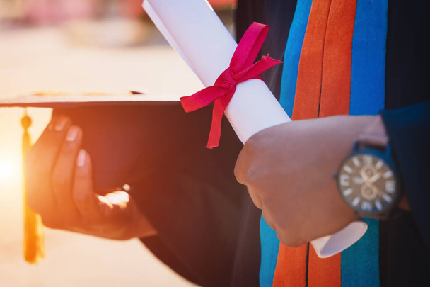 Foco seletivo e close-up de uma pós-graduação universitária detém um certificado de grau e boné de graduação celebra na cerimônia de formatura. - Foto, Imagem