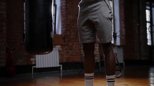 Un hombre afroamericano bombeando los músculos de sus manos con dos pesas en el gimnasio - Metraje, vídeo