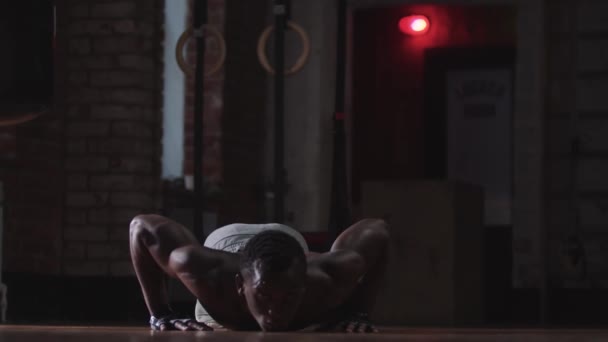 Entrenamiento en el gimnasio - un joven negro guapo sin camisa haciendo flexiones - Metraje, vídeo