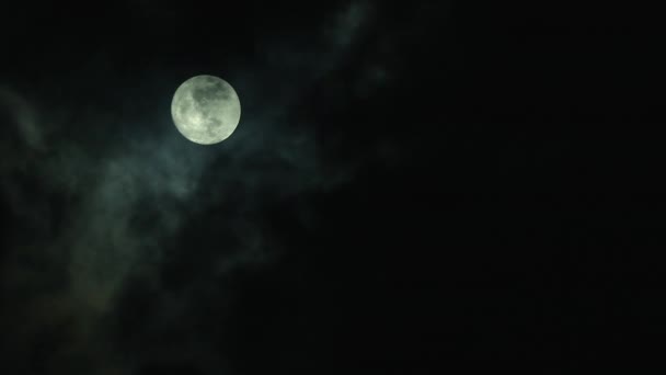 Beautiful full moon shining bright on dark sky. Fast moving black clouds passing over the moon at night, at real time. Outdoor at nighttime. - Footage, Video