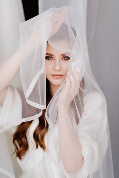 portrait of a beautiful young woman in a white robe under a wedding veil.  - Фото, зображення