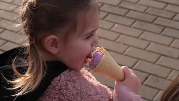 Niña come helado de frutas en cono de oblea en la calle - Imágenes, Vídeo