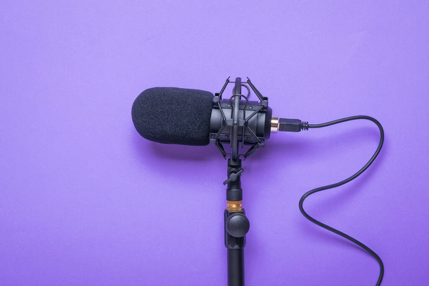 Micrófono con un cable atornillado al soporte sobre un fondo púrpura. Equipo de grabación de sonido. - Foto, Imagen