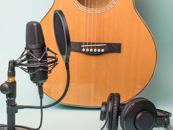 Gitarre, Mikrofon und Kopfhörer auf blauem Hintergrund. Musik aufnehmen und abspielen. - Foto, Bild