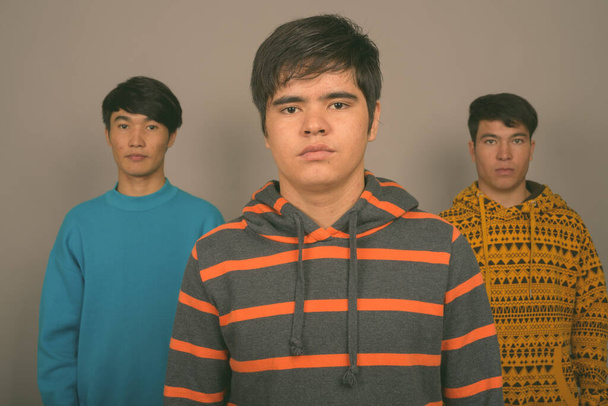 Gri arka planda üç genç Asyalı arkadaş - Fotoğraf, Görsel