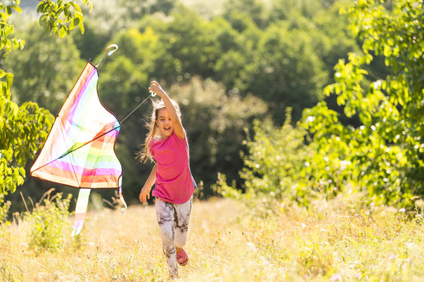 Little girl flying a kite running outdoor with a kite - Фото, зображення