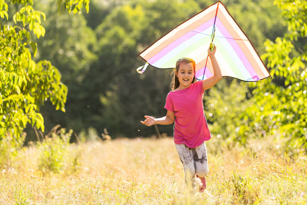 Little girl flying a kite running outdoor with a kite - 写真・画像