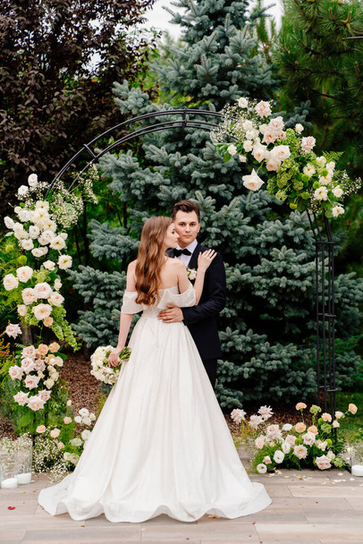 outdoor wedding ceremony in an arch of living flowers.Beautiful couple newlyweds - Foto, imagen