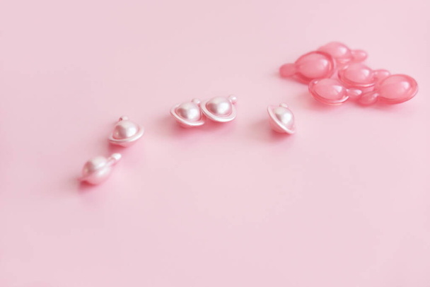 ροζ κάψουλες καλλυντικών σε ροζ φόντο. ορό ή κρέμα για τη θεραπεία του δέρματος. αναζωογονητικά πεπτίδια για ομορφιά και ηλικία που αψηφούν. - Φωτογραφία, εικόνα