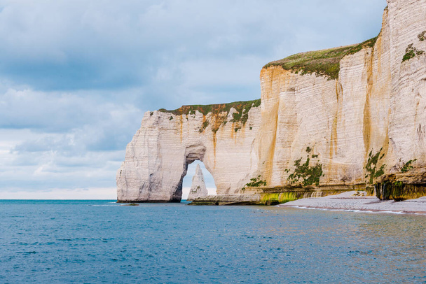 A view of the Etretat white cliffs at sunset. Cloudy blue sky. Normandy, France - Photo, Image