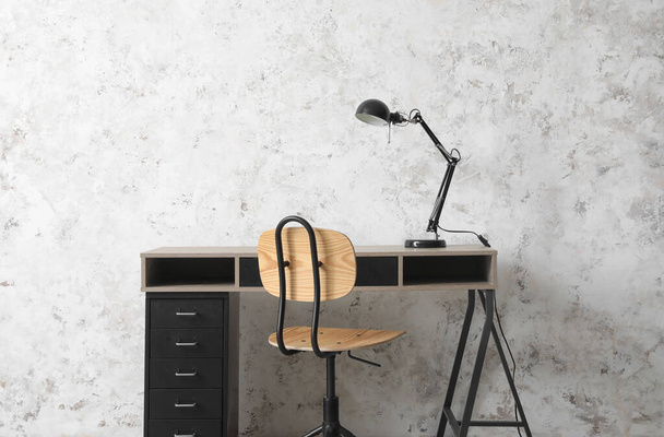 Stilvoller Tisch, Lampe und Stuhl gegen helle Wand im Zimmer - Foto, Bild
