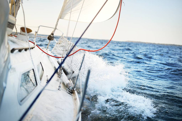 Weiße Schaluppe getakelte Jacht segeln an einem klaren, sonnigen Tag. Blick vom Deck auf Bug, Mast und Segel. Finnischer Meerbusen. Wellen und Wasser plätschern. Transport, Sport, Erholung, Freizeitaktivität - Foto, Bild