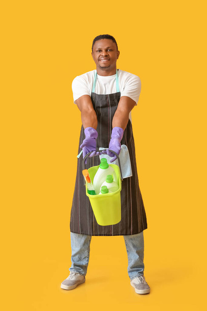 Afrikkalainen-amerikkalainen mies, jolla on puhdistustarvikkeita väritaustalla - Valokuva, kuva