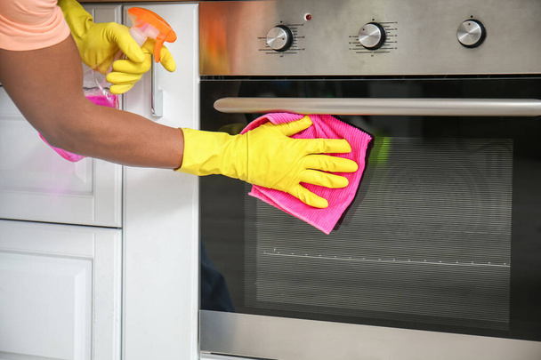Afroamerykanin czyści piekarnik w kuchni - Zdjęcie, obraz