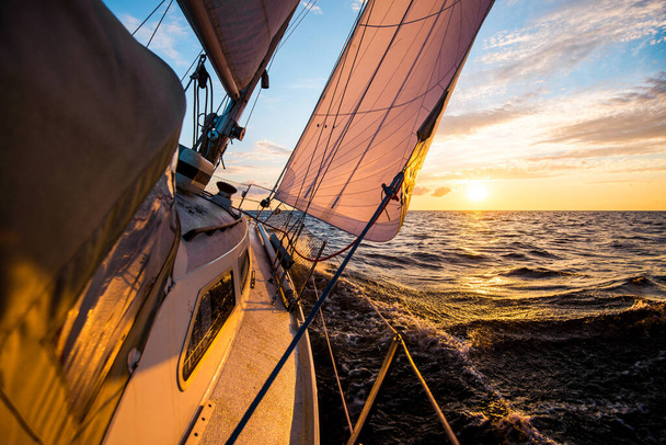 Біла яхта пливе на заході сонця. Вигляд з палуби на лук і вітрила. Хвилі та хмари. Балтійське море - Фото, зображення