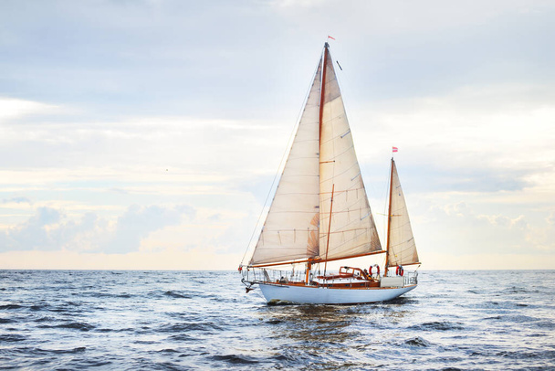 Vintage houten twee mast jacht (yawl) zeilen in een open zee op een heldere dag. Golven en witte wolken - Foto, afbeelding