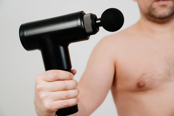 focus on subject. man holds a massage gun. medical-sports device.  - Photo, Image