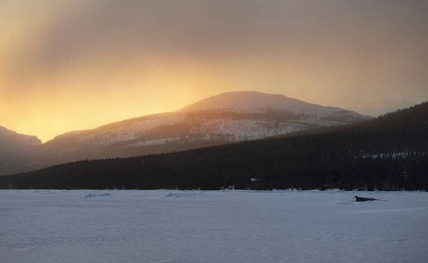 Kandalakshanlahden jääpainevyöhyke auringonlaskun aikaan. Värikkäitä pilviä. Veneen lähikuva. Taustalla Kuolan niemimaan vuoret ja havumetsät. Meri, Napapiiri, Karjala, Venäjä - Valokuva, kuva