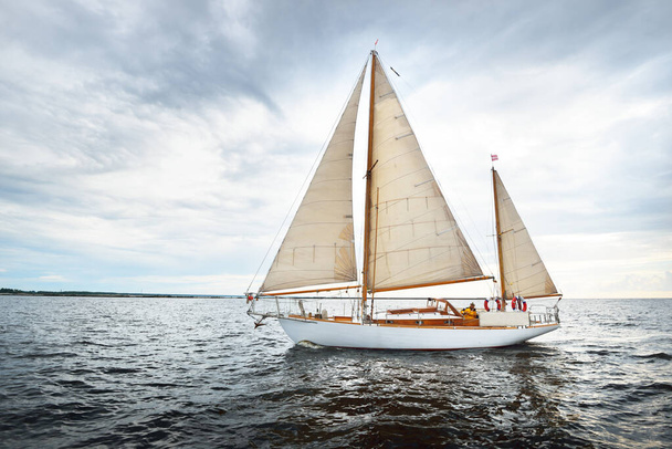 Vintage wooden two mast yacht (yawl) sailing in a open sea on a clear day. Waves and white clouds - Valokuva, kuva