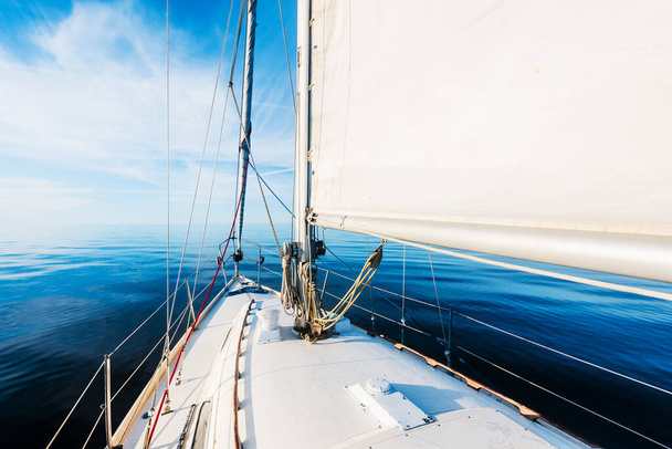 White sloop rigged yacht sailing in an open Baltic sea on a clear sunny day. A view from the deck to the bow, mast and sails. Estonia - Photo, Image
