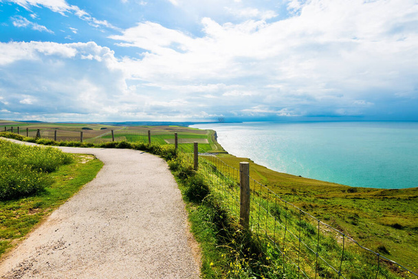 A country road through the valley near the cliffs of the English Channel. Green grass, azure water, clear blue sky. Idyllic summer scene. Cap Gris Nez, Pas-de-Calais, France - 写真・画像